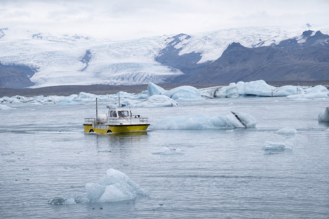 An amphibian boat cruising among icebergs on Jökulsárlón lagoon under the bright summer sky