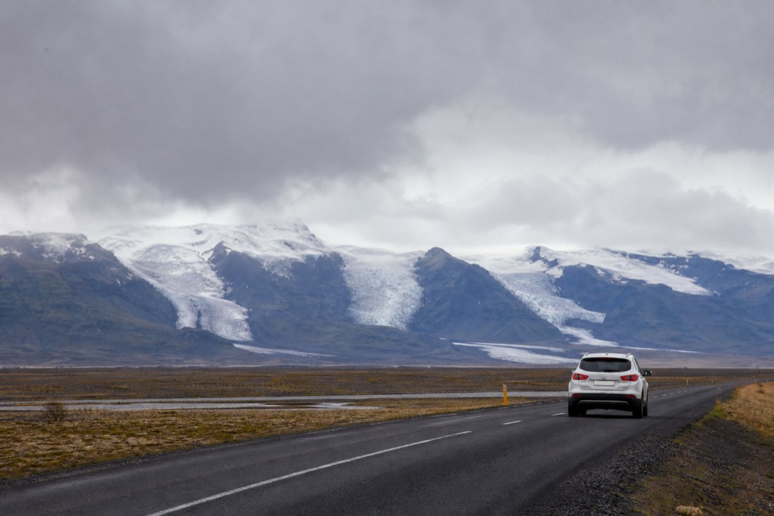 A rental car on Route 1 with Vatnajökull's glacier tongues in the distance on the drive to Jökulsárlón